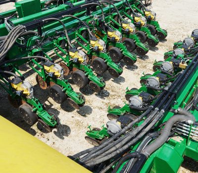 Close up of seeder attached to tractor in field. Agricultural machinery for spring works sowing, seeding
