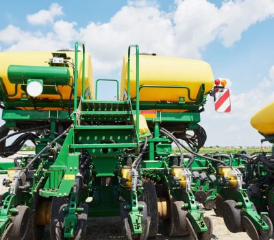 Close up of seeder attached to tractor in field. Agricultural machinery for spring works sowing, seeding