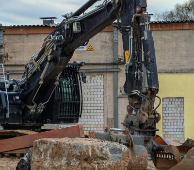 Heavy excavator machinery at a construction site with earth and concrete debris.